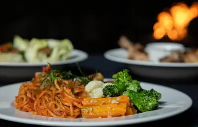 a plate of food with noodles and broccoli on a table at Dvara Luxury Resort Kodaikanal in Kodaikānāl