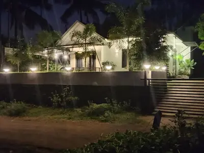a house with a fence and stairs at night at Teaside Inns in Vythiri