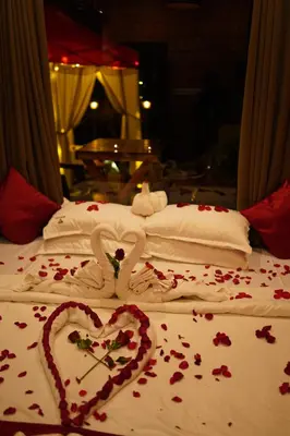a bed with two swans making a heart on it at Mount Stratus Resort Vayalada in Bālūssheri