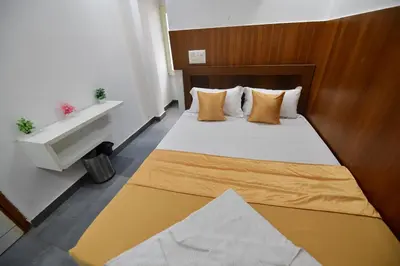 a small bedroom with a bed with orange pillows at Hotel Surya Lodge in Mysore