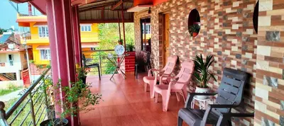a balcony with chairs and tables and a building at Holidayincoorg Royal Mansion in Madikeri