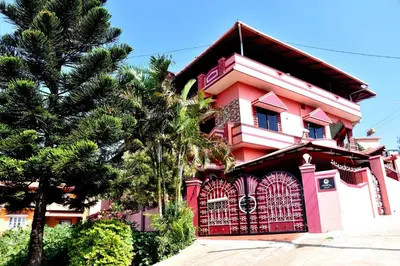 a pink house with a gate and a tree at Holidayincoorg Royal Mansion in Madikeri