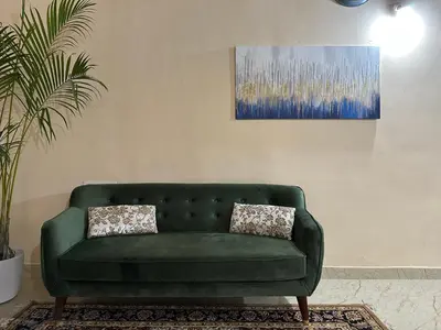 a green couch in a living room with a painting at Rustic Village Farmhouse in Bengaluru