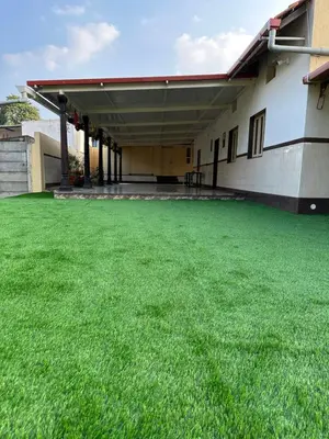 a large yard with green grass in front of a building at Rustic Village Farmhouse in Bengaluru
