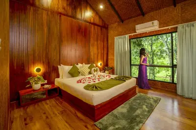 a woman standing in a bedroom with a bed and a window at Crystal Kuruva Nature Resort & Spa in Wayanad