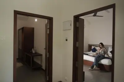 a woman sitting on a bed in a room at Crystal Kuruva Nature Resort & Spa in Wayanad