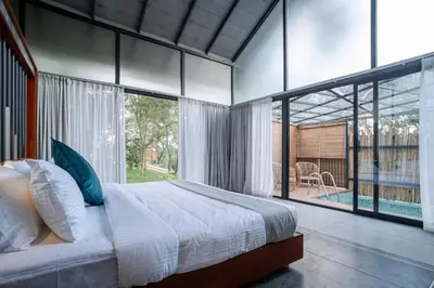 a bedroom with a large bed and a large window at Crystal Kuruva Nature Resort & Spa in Wayanad
