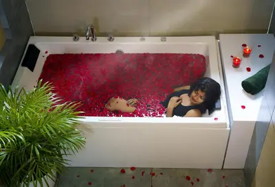 a woman is in a bathtub filled with redetti at Crystal Kuruva Nature Resort & Spa in Wayanad