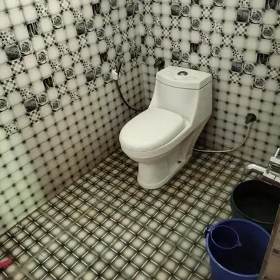 a bathroom with a toilet with a black and white shower curtain at GOLDEN HILL HOMESTAY WAYANAD in Panamaram