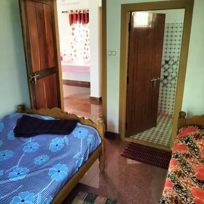 a bedroom with a bed and a mirror at GOLDEN HILL HOMESTAY WAYANAD in Panamaram