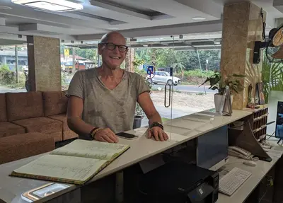 an older man sitting at a desk with a table at Dreams Paradise Airport Residency in Nedumbassery