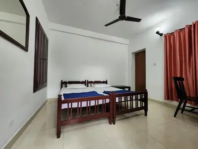 a bedroom with a bed and a ceiling fan at Navarang Villa in Kalpetta