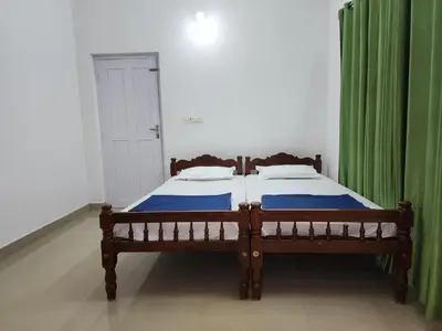 a bedroom with a wooden bed with green curtains at Navarang Villa in Kalpetta