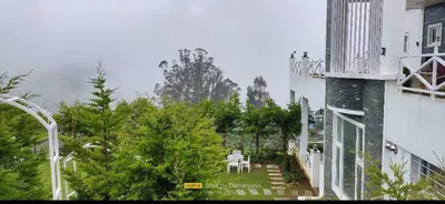 a balcony of a building with a table and chairs at Orchard Valley View in Ooty