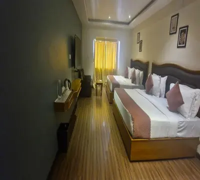 a hotel room with two beds and a television at Hotel Glanton Manor in Ooty