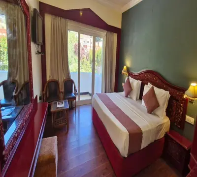 a hotel room with a bed and a window at Hotel Glanton Manor in Ooty