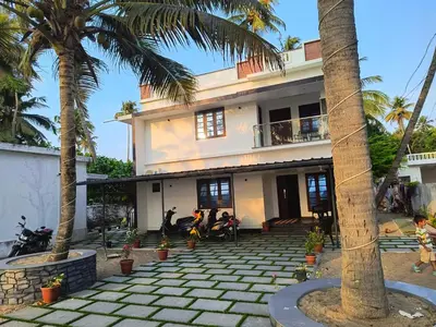 a building with palm trees in front of it at ENOCEAN HOMESTAY in Cherai Beach