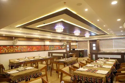 a restaurant with tables and chairs in a room at VKJ INTERNATIONAL in Perumbavoor