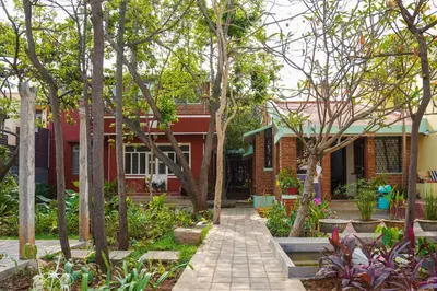 a walkway in front of a house with trees at Rahees Bi Roambay - Backpacker Hostel in Mysore