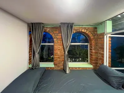 a bed in a room with two windows at Rahees Bi Roambay - Backpacker Hostel in Mysore