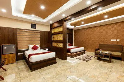 a bedroom with two beds and a tv in a room at MARZA INN in Kalpetta