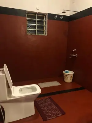 a bathroom with a toilet and a window at Amberleaf Estate 4BHK Homestay Coorg by Homeyhuts in Virajpet