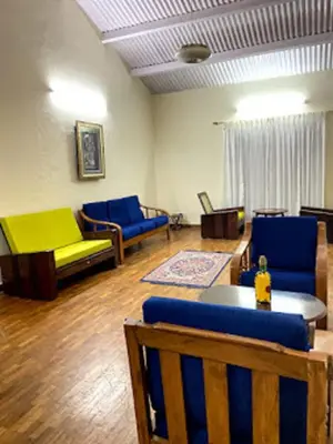 a living room with blue and yellow couches and a table at Dew Drops Cottage Coonoor By Lexstays in Coonoor