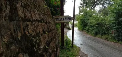 a street sign on a wall next to a road at Dew Drops Cottage Coonoor By Lexstays in Coonoor