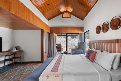 a bedroom with a bed and a desk in a room at WelcomHeritage Ayatana Ooty in Ooty