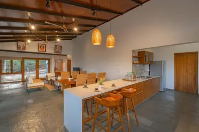 a kitchen and dining room with a counter and chairs at StayVista at Mountain Rain - Breakfast Included in Wayanad