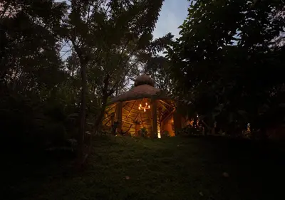 a house with a lit up room in the woods at Chembarathi Wayanad Boutique Resort in Vaduvanchal