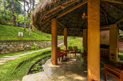 a pavilion with wooden benches and a stone wall at Chembarathi Wayanad Boutique Resort in Vaduvanchal