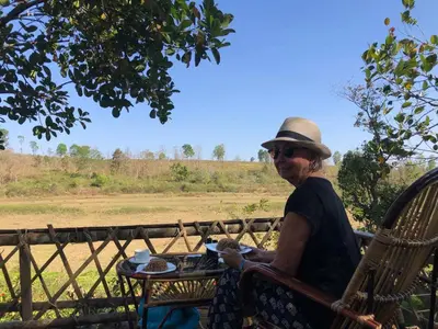 a woman in a hat sitting at a table at Lotus Jewel Forest Camping in Sultan Bathery