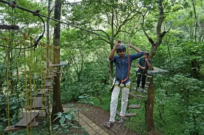 two people on a zip line in a forest at Coffee Acres Resort in Kalpetta