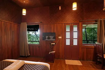 a bedroom with wooden walls and a tv and a bed at Coffee Acres Resort in Kalpetta