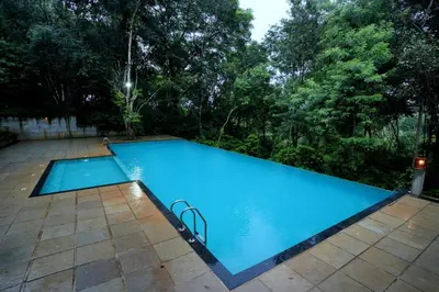 an empty swimming pool in a yard with trees at Coffee Acres Resort in Kalpetta