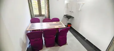 a table with purple chairs in a room at Johns Villa in Sultan Bathery