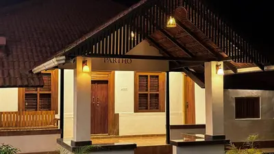 a house with a front porch with a wooden door at PARTHO home stay in Padinjarathara