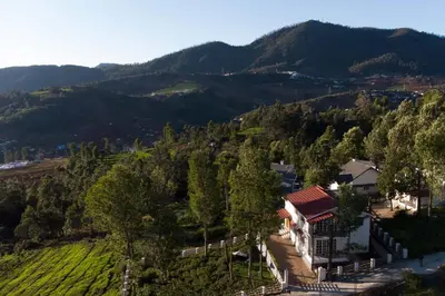 a house on a hill with mountains in the background at StayVista at Villa Misty Oaks with Breakfast in Ooty