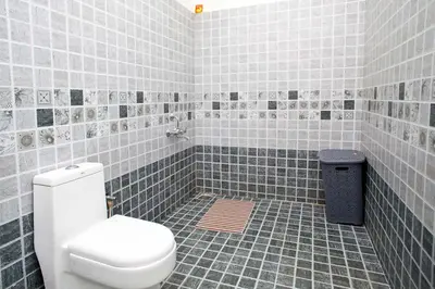 a tiled bathroom with a toilet and a trash can at StayVista at Villa Misty Oaks with Breakfast in Ooty