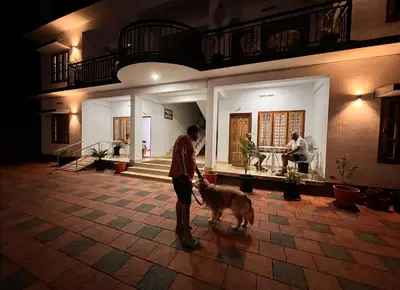 a man with a dog in front of a house at Casa Maria Mystica apartments, Mananthavady, Wayanad in Mānantoddy