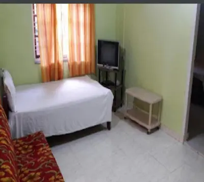 a bedroom with a bed and a tv and a couch at Devarakadu Valley View by StayApart in Madikeri