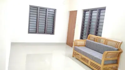 a couch sitting in a room with two windows at Eve's appartment in Meppādi