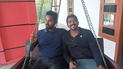 two men are sitting on a swing at CRS RED & WHITE HOMESTAY in Sultan Bathery