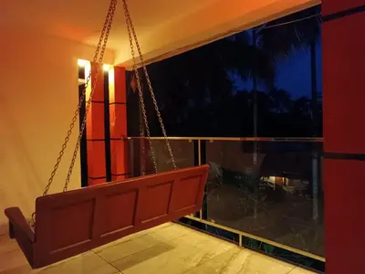 a swinging bench in a room with a window at CRS RED & WHITE HOMESTAY in Sultan Bathery