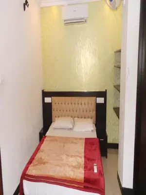 a small bedroom with a bed with a red blanket at Redbell suites Residency in Kondotti