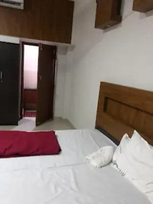 a bedroom with a white bed with a wooden headboard at Redbell suites Residency in Kondotti