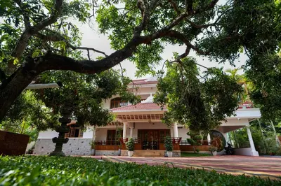 a building with a tree in front of it at Parudeesa - Heavenly- Luxurious Palace look-Near CBD - Kerala - India with Breakfast in Kāladi
