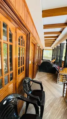 a room with two chairs and a bed in a house at Golden Cypress Resort with Pool -Wayanad in Padinjarathara