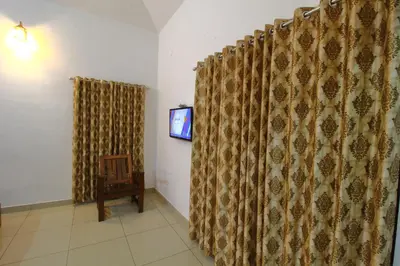 a room with a curtain and a tv and a chair at TreeSong Villa - Tranquil Forest Villa in Wayanad in Sultan Bathery
